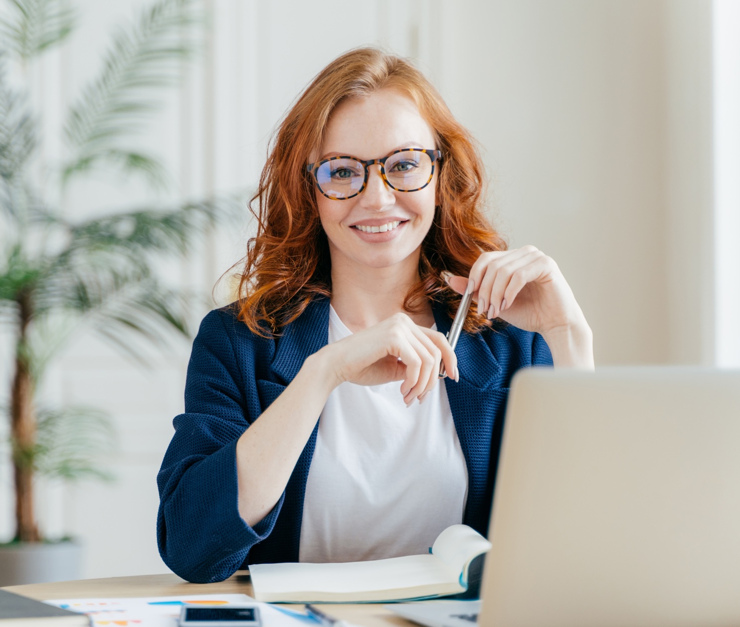 Portrait of happy redhaired woman employee in optical glasses.