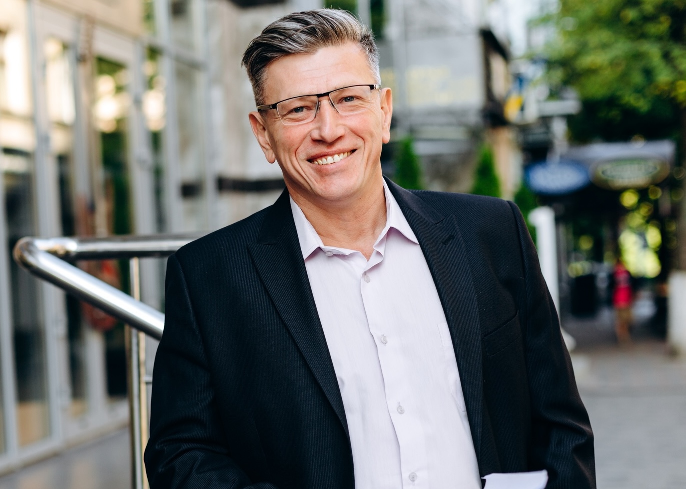 Smiling senior businessman in glasses holding a  document and looking at the camera